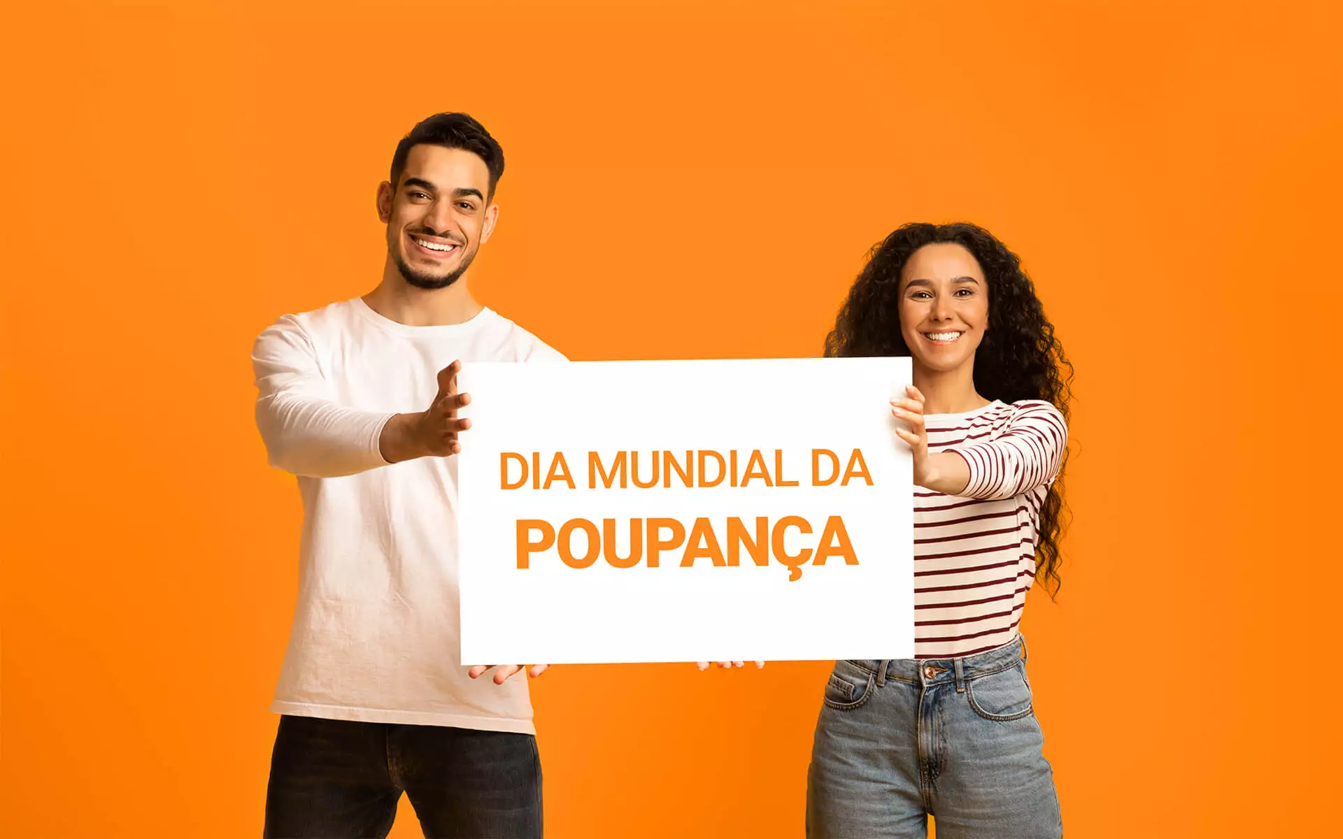 Dois jovens morenos sorridentes e ativos seguram cartaz branco sobre fundo laranja.